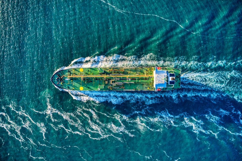 aerial-view-of-white-and-yellow-boat-on-body-of-water-during-daytime-tm-pbz5uhiu Green oil tanker headed out to sea aerial