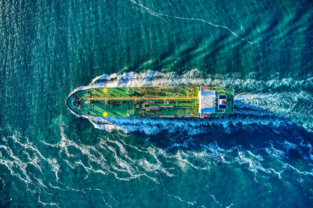 Green oil tanker headed out to sea aerial
